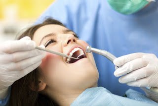 A woman smiling while she gets her teeth cleaned at the dentist in Independence, MO