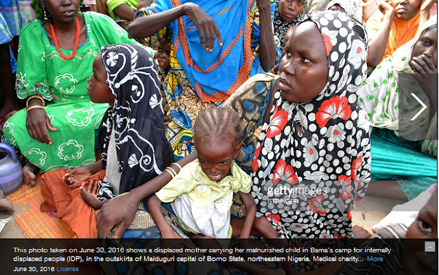 This photo taken on June 30, 2016 shows a displaced mother carrying her malnurished child in Bama's camp for internally displaced people (IDP), in the outskirts of Maiduguri capital of Borno State, northeastern Nigeria. Medical charity Doctors Without Borders (MSF) last week warned 'a catastrophic humanitarian emergency' was unfolding at the camp for internally displaced people (IDP) in Bama. At least 188 people died between May 23 and June 22, mainly from diarrhea and malnutrition, while more than 1,200 graves, many of them for children, had been dug near the camp in the last year, it added. / AFP / STRINGER