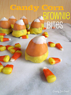 brownie bites dipped in chocolate to look like candy corn on marble slab with candy corn around