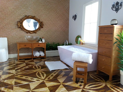 One-twelfth scale modern miniature luxury bathroom with a pasific theme. Under the window is a tub filled with bubbles, and next to the windows, wall-mounted candles. The sink is on a colonial sideboard and there is a bronze ornamental mirror above. There are plenty of white fluffy towels rolled up, and a glass of sparkling wine sits on the side of the bath under the window,