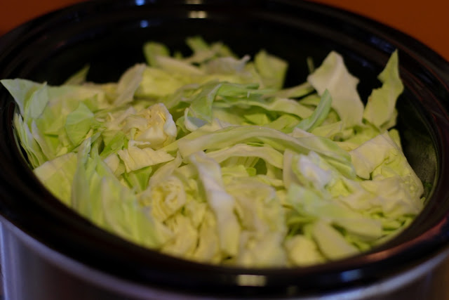Cabbage being added to the crock pot. 