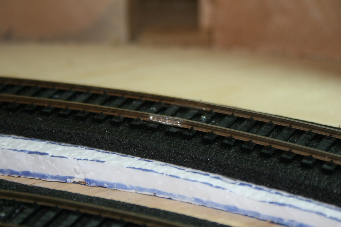 Installed metal track terminal connectors with soldered power leads leading below foam roadbed