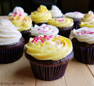chocolate cupcakes with yellow and white sweetened condensed milk buttercream piped on top and sprinkles