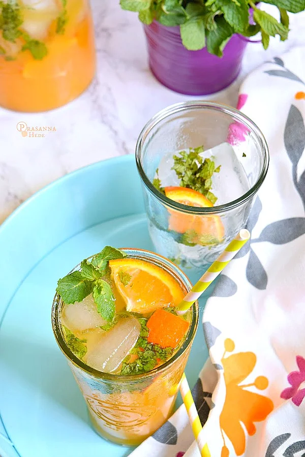 Non Alchholic Orange Mojito served in a blue tray with orange wedges,mint leaves and lots of ice