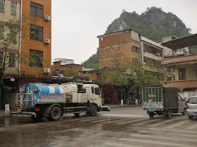 Pingfeng Hill (屏峰山) and water truck spraying water onto the road in Yunfu