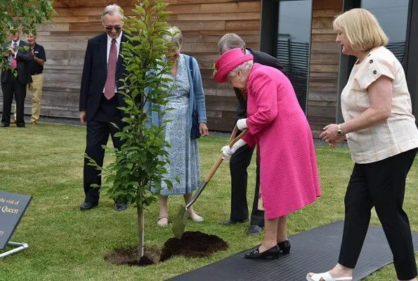 Queen Elizabeth wore a floral satin dress, pink coat and pink hat, pearl necklace, pearl earrings and diamond brooch