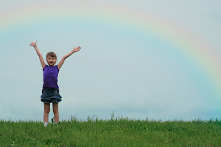 little girl in front of a rainbow