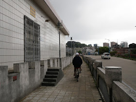 man riding a bike on a wall bordering the Gui River (桂江) in Wuzhou (梧州)
