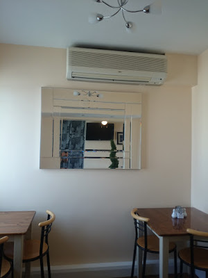 magnolia-cream cafe interior with wall mounted blower heater, and mirrors facing each other