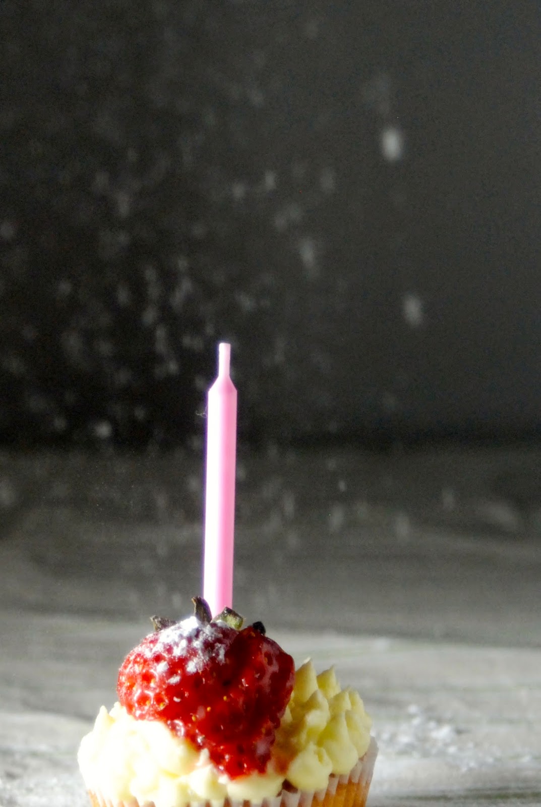 cupcake with birthday candle and falling icing sugar