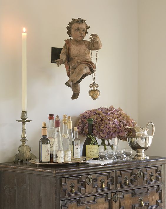 Antique Spanish Colonial campaign table used as bar with magnificent antique cherub and ex voto milagro hear presiding over it in the Santa Fe home of Peter Vitale. #frenchcountry #frenchantiques #interiordesign #petervitale