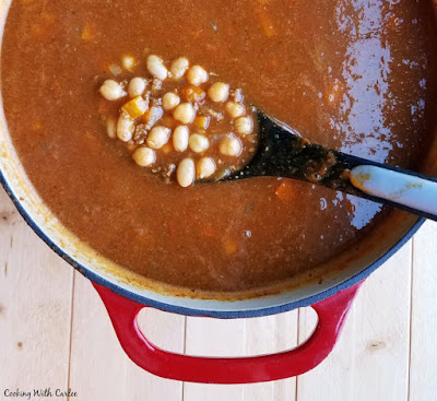 Cozy up with a bowl of apple ale pumpkin chili and it is sure to warm you from the inside out. It screams fall with pumpkin, apple, beer, and chili all together in one bowl. Make a big pot and get your favorite toppings ready. It is perfect for any time, but especially for game day! spoon full of beans and ground turkey over big enameled cast iron pot of apple ale pumpkin chili
