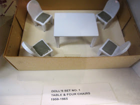 Set of metal dolls' house table and chairs displayed in its box.