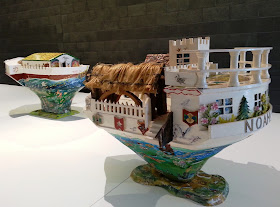 Two miniature wooden painted artist's arks on display in a gallery.