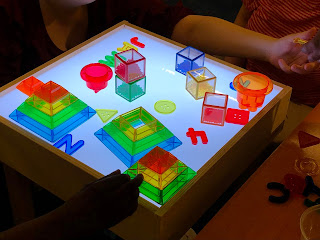 wood light table with colorful translucent blocks, letters, numbers, and pyramid shapes