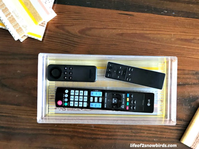 Remote controls in a box on a table.