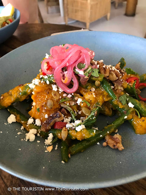 Pumpkin salad with beans and feta cheese served on a grey plate.