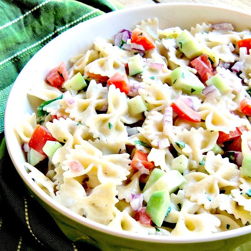 Mediterranean Pasta Salad is A simple pasta salad recipe that uses only 7 ingredients. It is fresh, light, and the perfect BBQ or picnic side. #pasta #salad #easy #recipe #mediterranean | bobbiskozykitchen.com Mediterranean Pasta Salad in a bowl with a green striped hand towel in the background on a wooden background