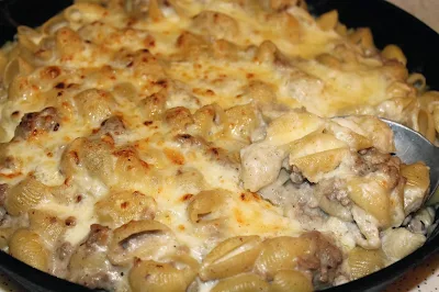 Spoon scooping apple and pork macaroni and cheese.