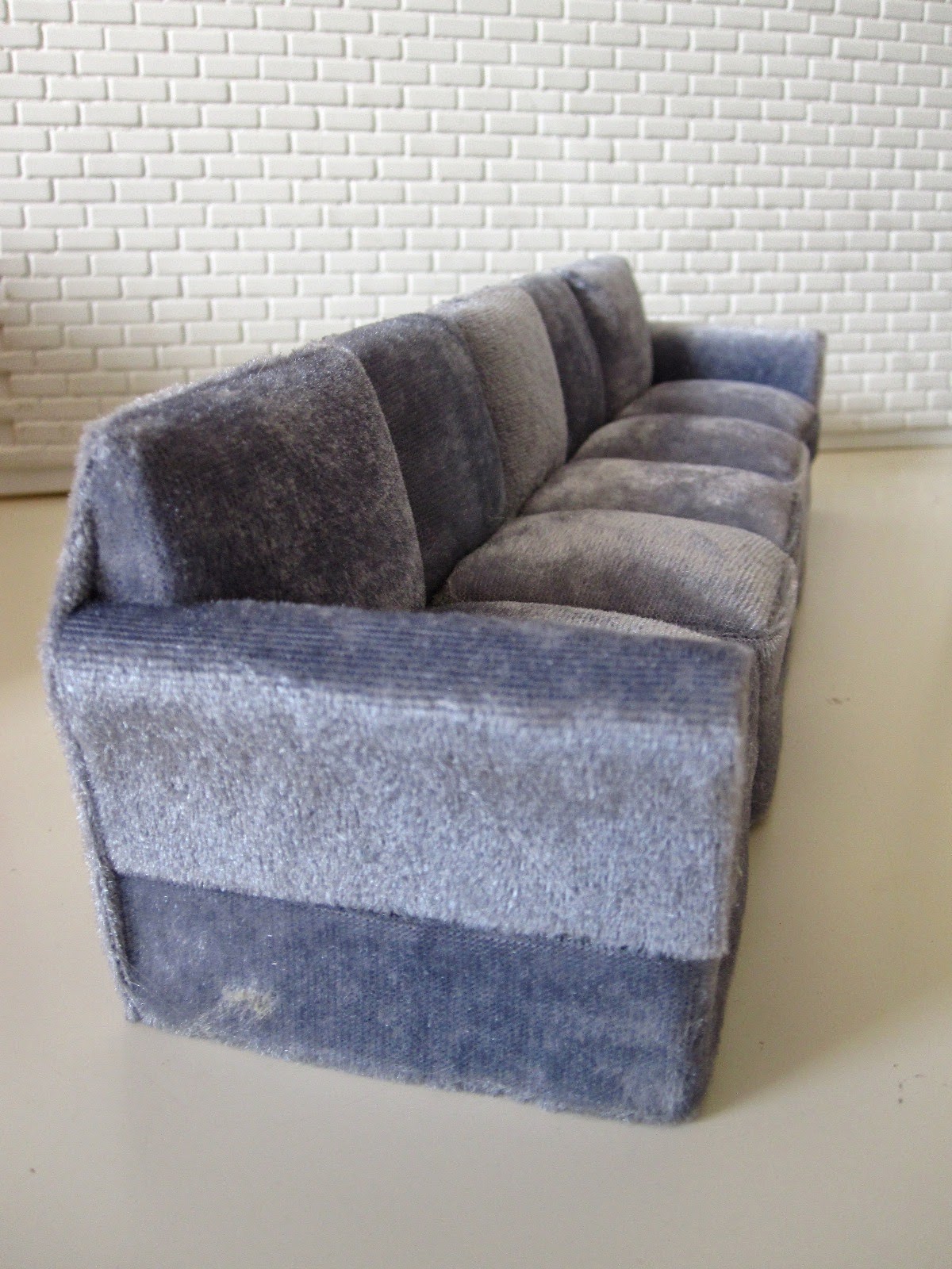 Modern miniature five seater grey velvet sofa.