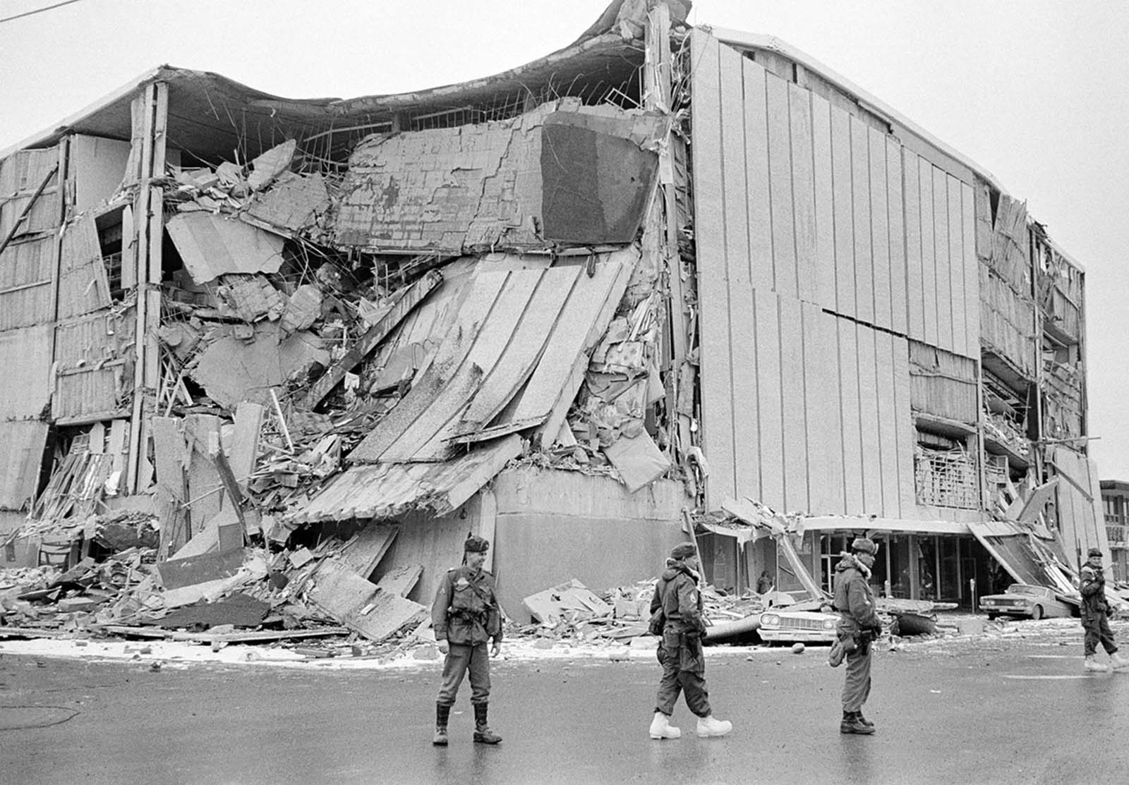 With the city under martial law, soldiers patrol a downtown street in Anchorage, Alaska, on March 28, 1964. In background is the wreckage of the five-story J.C. Penney's store at Fifth Avenue and D Street.