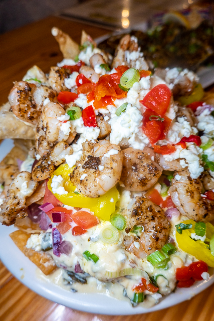 Greek Shrimp Nachos from FloraBama Yacht Club - Fried wonton chips smothered in a spinach-feta-cream sauce topped with grilled Gulf shrimp, tomatoes, crumbled feta, Kalamata olives, peppadews, banana peppers, green onion, and red onion Greek Shrimp Nachos from FloraBama Yacht Club - Fried wonton chips smothered in a spinach-feta-cream sauce topped with grilled Gulf shrimp, tomatoes, crumbled feta, Kalamata olives, peppadews, banana peppers, green onion, and red onion