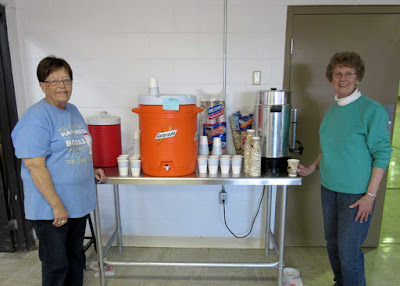 two women post by drink station offering punch, coffee, etc.