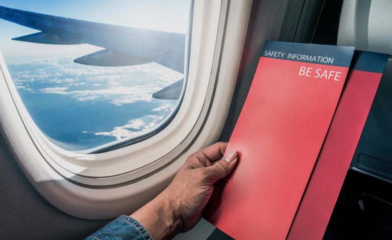 Asian man read flight safety instructions on card board flight. Blank safety instructions on board for passenger and traveler safety.