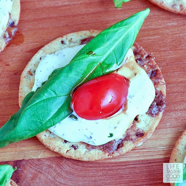 Caprese Crackers | by Life Tastes Good are gluten free, bite sized morsels of deliciousness! Topped with a garlic and herb cheese spread, fresh basil leaves, tomatoes, and a drizzle of balsamic dressing, these appetizer bites are tasty any time of day, and especially perfect for a party, as they are easy to make and so enjoyable to eat!