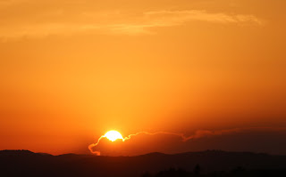 The sun descends behind a distant cloud The sun descends behind a distant cloud
