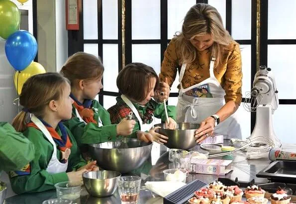 Queen Maxima wore a floral print satin yellow top and floral print blue skirt by Natan. Queen Maxima visited the Scouting Netherlands Cubs