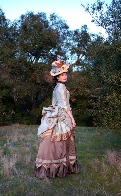 woman wearing blue and brown victorian dress with a bustle skirt and top hat
