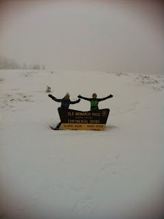 Two ladies snowshoeing at the top of Old Monarch Pass around the Continental Divide sign.