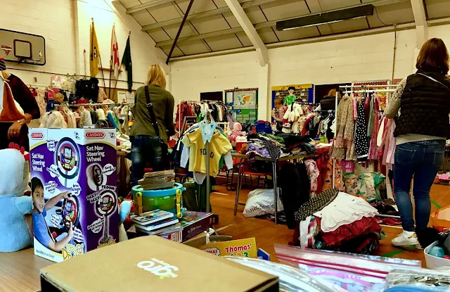 A view from the corner of the scout hall looking out towards lots of tables piled high with second hand children's clothes and toys