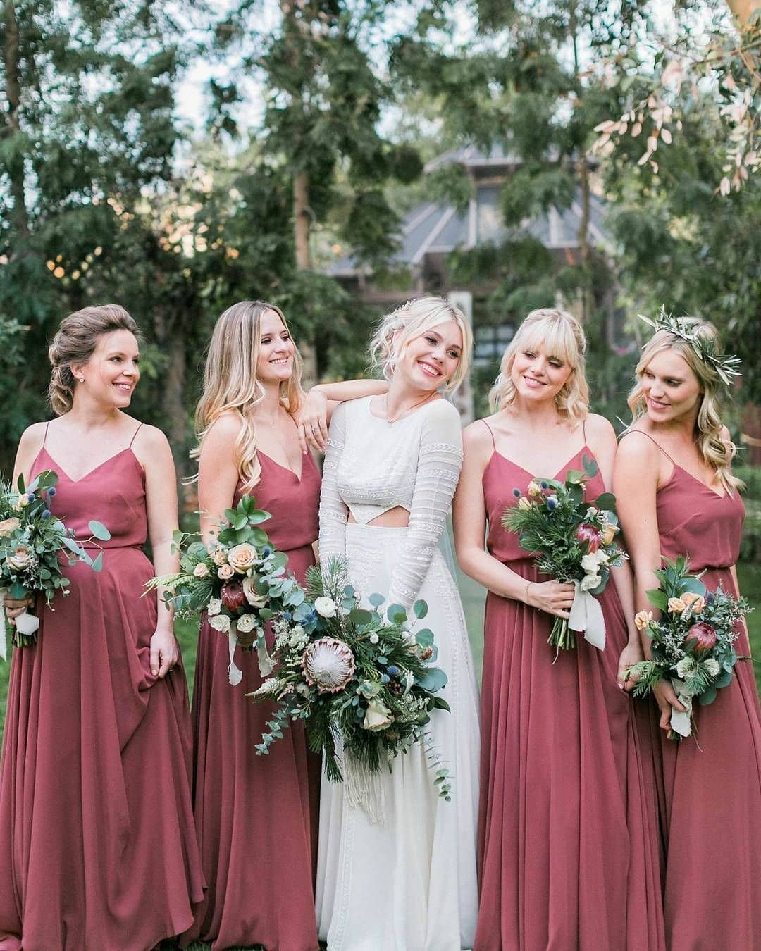 happy bridesmaids surround a bride in a wedding dress