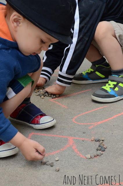 Child tracing letters made out of sidewalk chalk