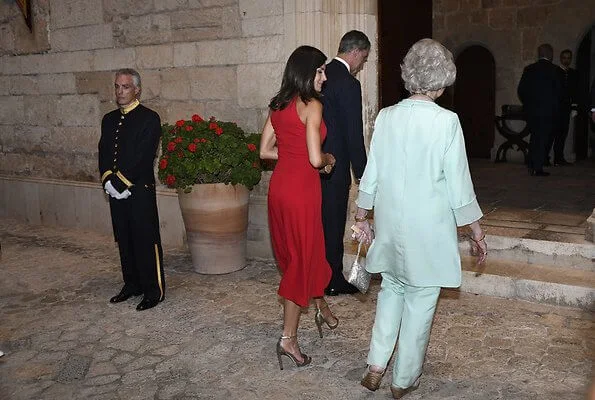 scoop neckline sleeveless fit and flare red dress. Dolce & Gabbana ready-to-wear collection, gold clutch. Queen Sofia