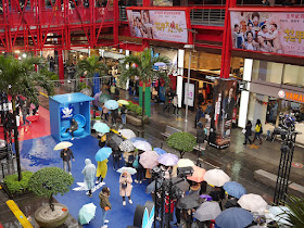 people with umbrellas waiting in line to take photos at an Adidas promotion