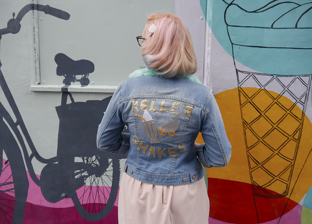 Vintage inspired fashion blogger Kimberley from Wardrobe Converations with candy coloured hair and DIY retro denim jacket with Roller Skates embellishment on back