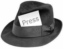 Fedora hat with "PRESS" card stuck in the hat band