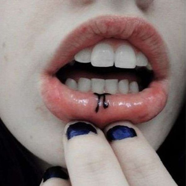 boca de mujer que nos enseña en el labio un tatuaje de la letra pi del alfabeto griego
