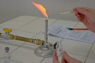 Teste de chama do cálcio, sendo feito com uma pequena amostra de cobre que foi umedecida com acido clorídrico concentrado, e colocada na chama do bico de bunsen com um fio de platina. teste de chama do calcio