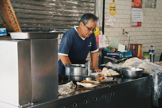 一旁的工作台正現擀著蛋餅皮，準備下鍋油炸。