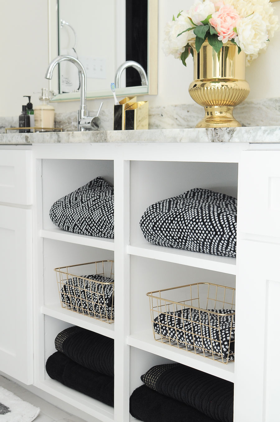 Black and white towels paired with gold baskets look gorgeous on the open shelves of this master bathroom vanity. The whole space is just gorgeous! Black and white towels paired with gold baskets look gorgeous on the open shelves of this master bathroom vanity. The whole space is just gorgeous!