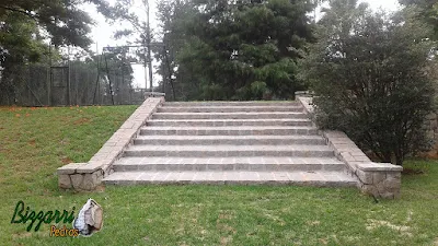 Piso de pedra nos patamares da escada de pedra no jardim com a mureta de pedra com o muro de pedra, as capas do muro com pedra tipo paralelepípedo rachado. Piso de pedra no patamar da escada rejuntado com massa e piso de pedra com junta de grama.