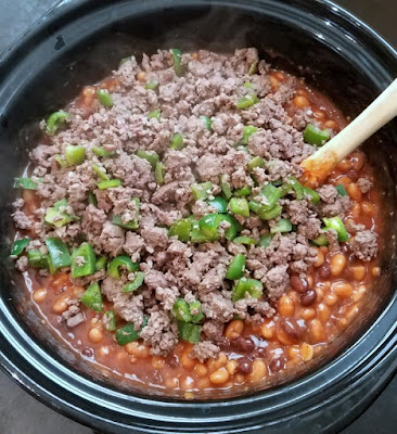 ground beef and diced green peppers on top of beans in slow cooker