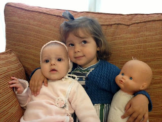 Niña con hermana pequeña y muñeca.
