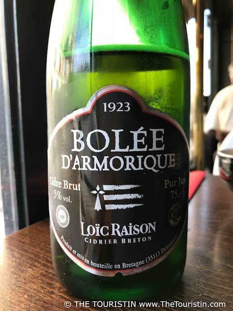 A green bottle of cider with a black, silver and red label.