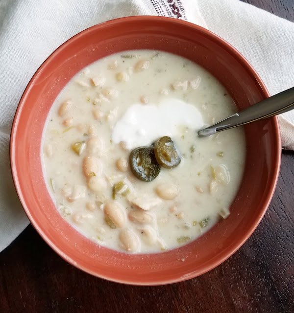 Creamy white chicken chili is a perfect cold weather meal. Make it for game day or any day to warm up from the inside out. close bowl of creamy white chicken chili with sour cream and jalapenos