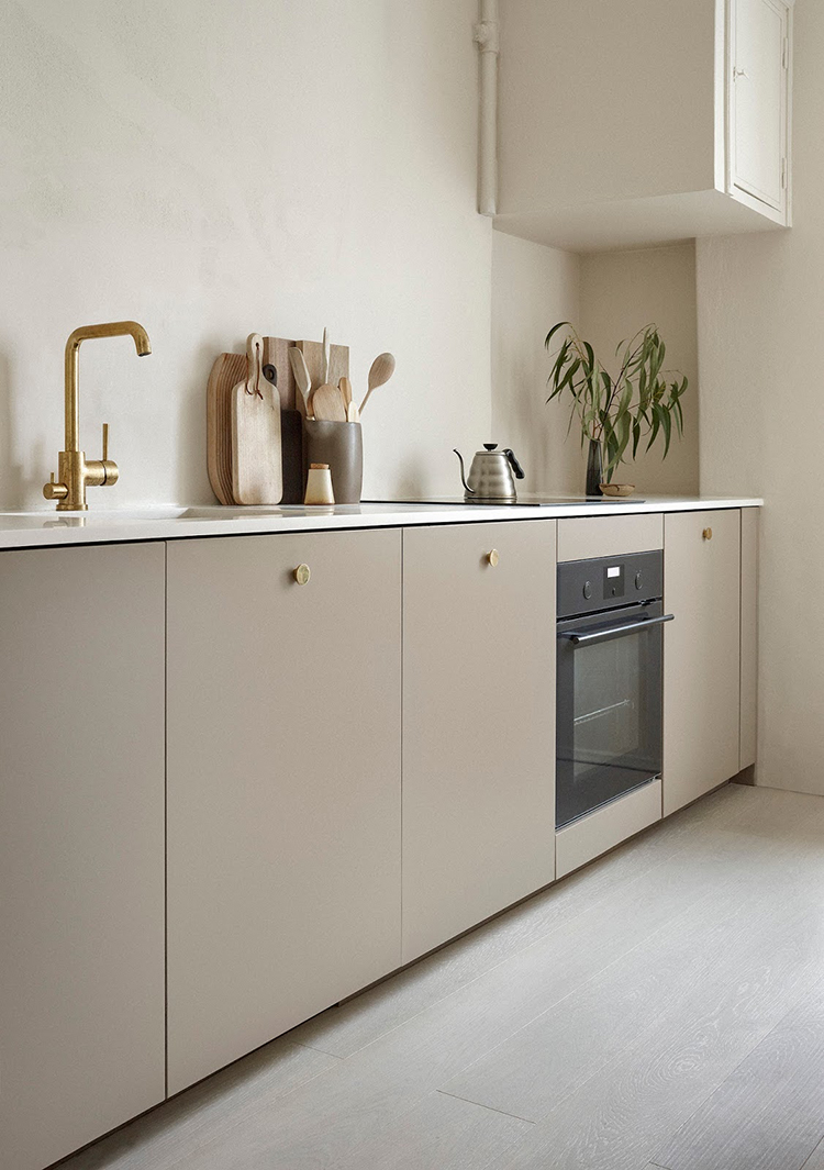 Kitchen with beige cabinets and brass details by Anna Pirkola. Photo by Katri Kapanen